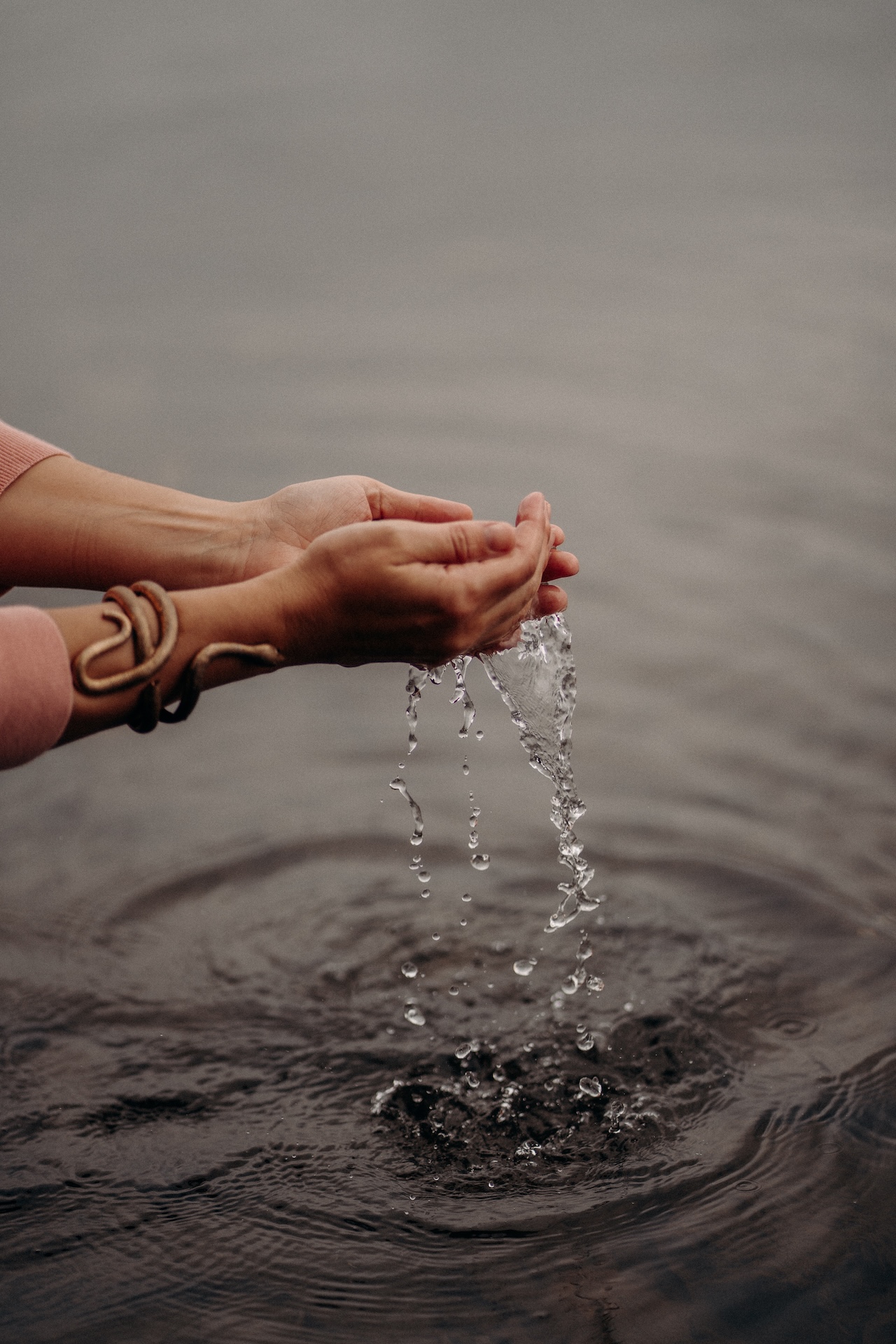 Cupped hands lifting water, ripples spreading